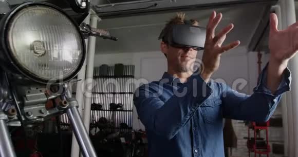 男机修工在摩托车修理厂4k中使用虚拟现实耳机视频的预览图