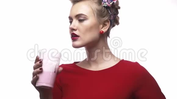 穿着红裙子的可爱金发女孩正在喝奶昔和眨眼视频的预览图