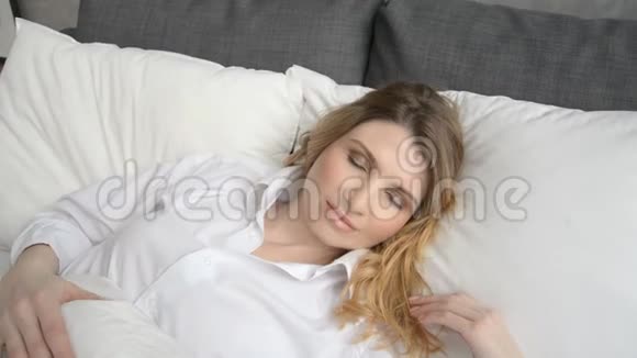 美丽的金发女人在早晨慢慢醒来视频的预览图