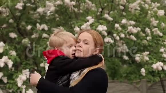 母子俩在春风中漫步在公园里紧紧地拥抱在一起视频的预览图