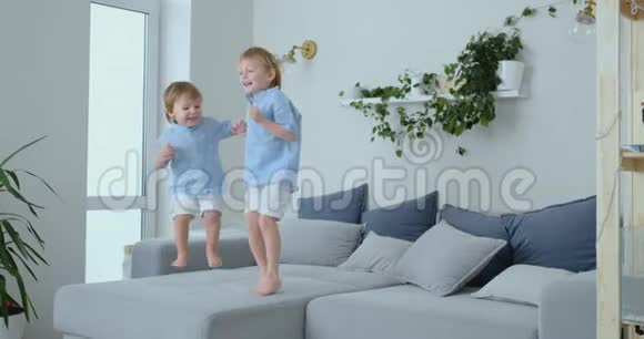 两个小男孩的兄弟在沙发上跳着玩欢乐欢笑和在家的乐趣快乐的童年视频的预览图