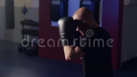 拳击手套中肌肉发达的拳击手在健身房用影子击球动作缓慢微光场景视频的预览图