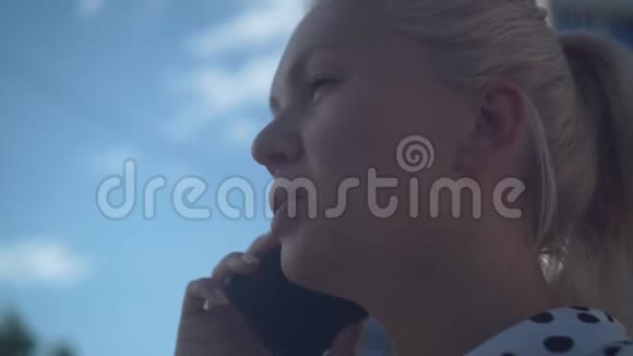 穿着白衬衫和黑豆的白人商务女性在电话里对着蓝天和云彩说话视频的预览图