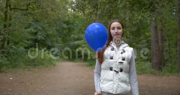 快乐的女孩站在一个蓝色的气球和微笑在一个木头在斯洛文尼亚视频的预览图