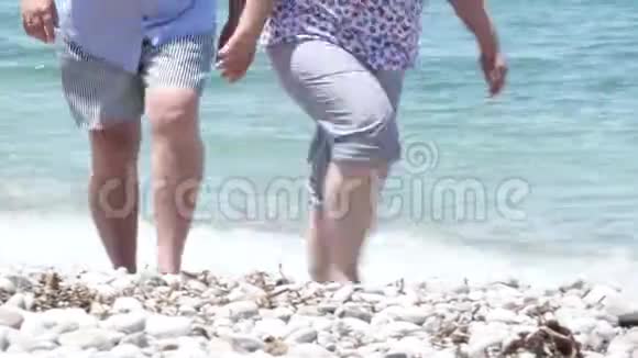 中年夫妇在白色的沙石海滩上靠近清澈的地中海视频的预览图