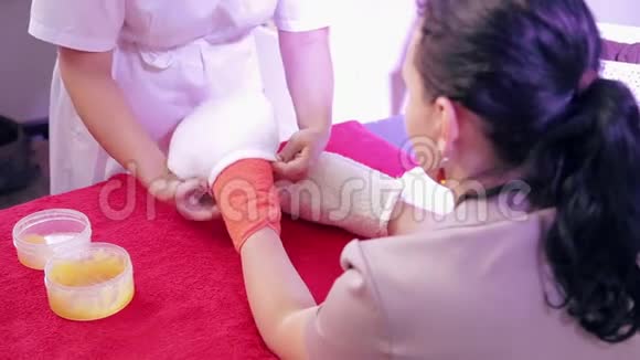 在手工石蜡治疗过程中美容师给病人戴上了手套视频的预览图