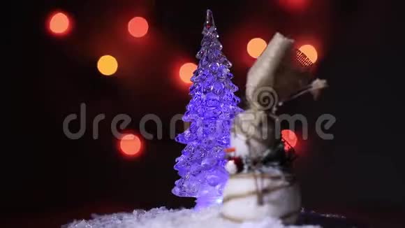 雪人在色彩斑斓的火光背景下绕着圣诞枞树跳舞视频的预览图