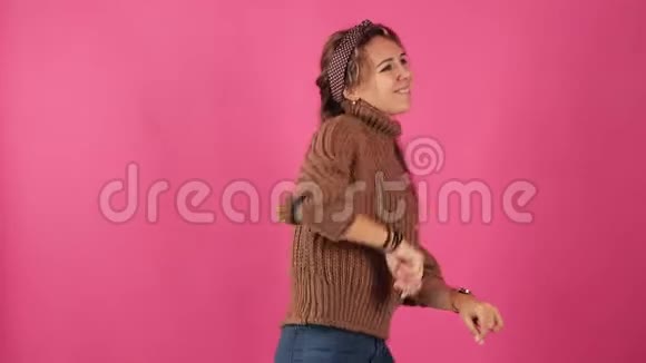 可爱漂亮的女孩穿着一件巧克力毛衣精力充沛舞蹈很棒孤独粉红色的背景视频的预览图