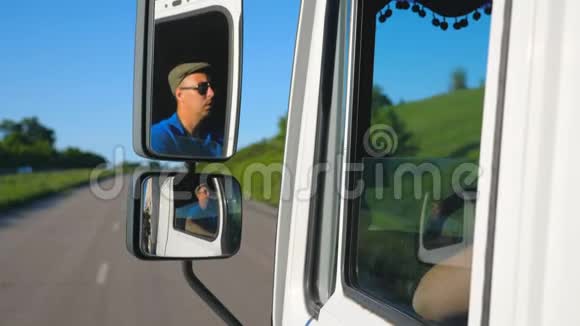 卡车司机戴着太阳镜在移动汽车的侧面镜子里反射男子驾驶卡车通过视频的预览图