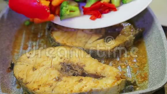 一个女人把新鲜的彩色蔬菜和鱼放在煎锅里视频的预览图
