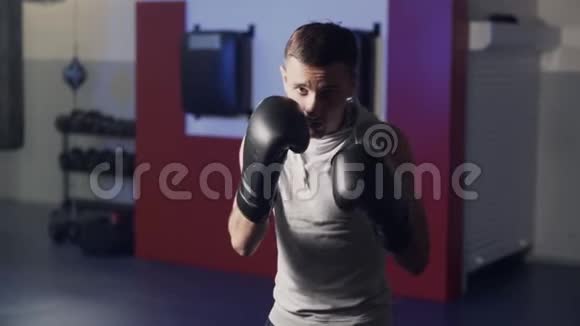 拳击手带着拳击手套在健身房的摄像机上打拳打影子慢动作视频的预览图