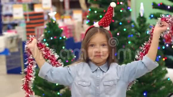 超市里一个有趣的小女孩用花环玩耍和跳舞圣诞节视频的预览图