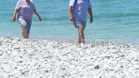 中年夫妇在白色的沙石海滩上靠近清澈的地中海视频的预览图