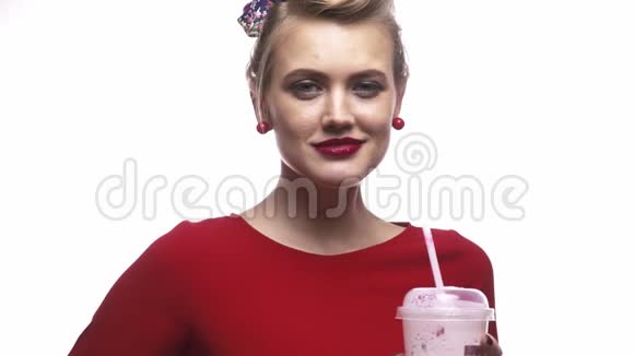 穿着红裙子的性感金发女孩微笑着拿着奶昔慢动作视频的预览图