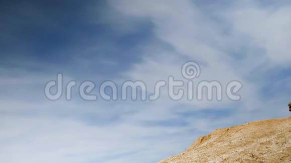 一位旅行者在一片美丽的蓝天的背景下走到一个沙石场的边缘拿出他的智能手机了视频的预览图