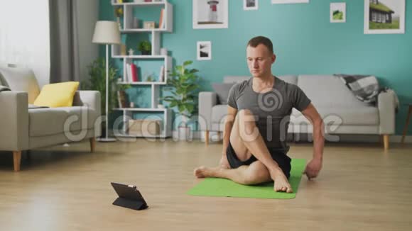 一个年轻人用平板电脑上的指令学习瑜伽视频的预览图