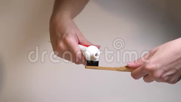 用手挤压木制牙刷上的牙膏刷牙每天的早晨孤立无援口腔卫生菌斑预防CC视频的预览图