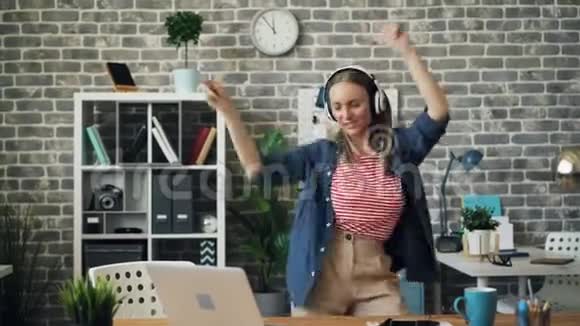 疯狂的企业家在办公室跳舞通过耳机听音乐视频的预览图