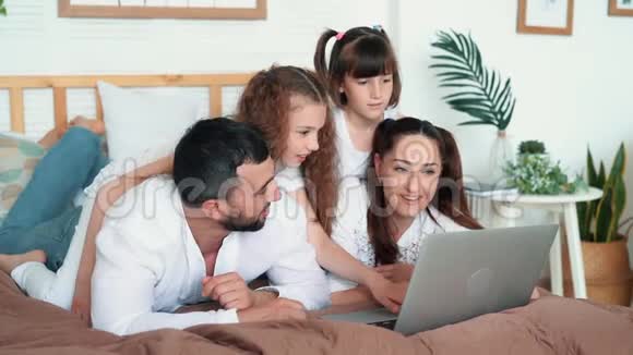 爸爸妈妈和两个女儿在笔记本电脑上玩电脑游戏慢动作视频的预览图