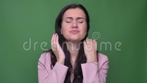 深色女商人穿着粉红色夹克做按摩的肖像绿色背景下头痛视频的预览图
