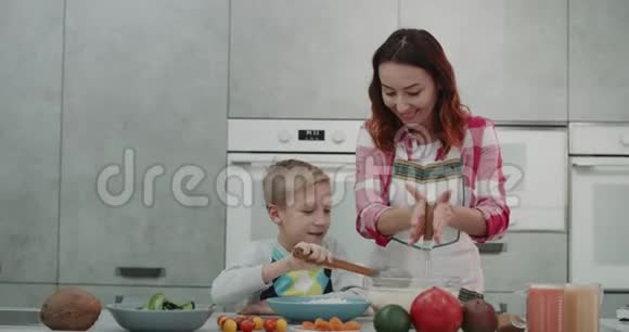 成熟的妈妈和他9岁的儿子一起在厨房做饭可爱的气氛视频的预览图