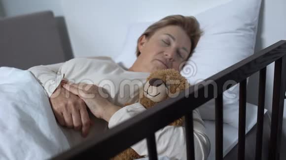 照顾与泰迪熊睡觉的女性病人的护士视频的预览图