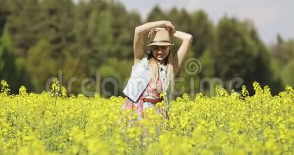 一个穿着裙子的快乐女人在夏天的黄色田野里跳舞视频的预览图
