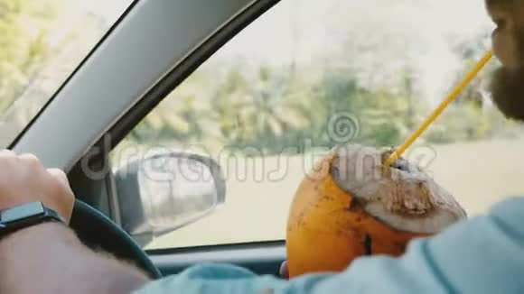 在热带度假时用智能手表驾驶汽车近距离拍摄男性双手手持异国情调的水果饮料视频的预览图