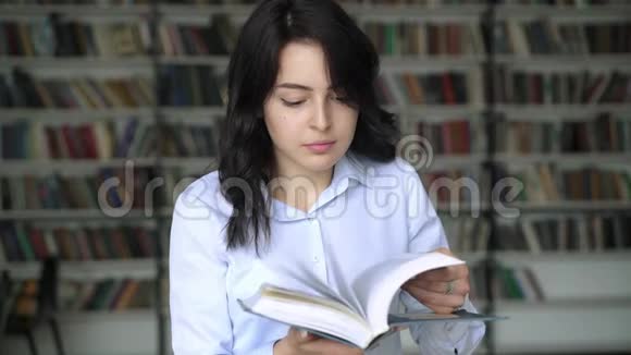 翻翻图书馆书架背景的百科全书的年轻女子视频的预览图