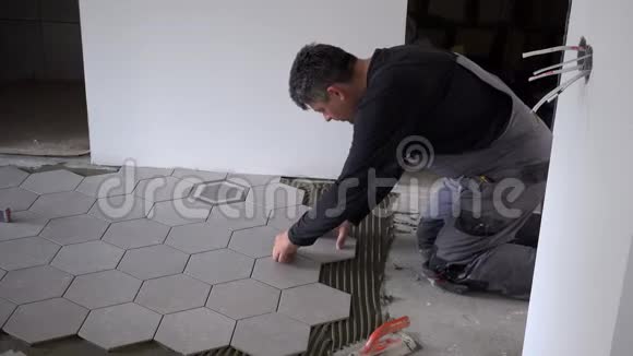 在建的新公寓里Handyman在地板上铺设六边形瓷砖视频的预览图
