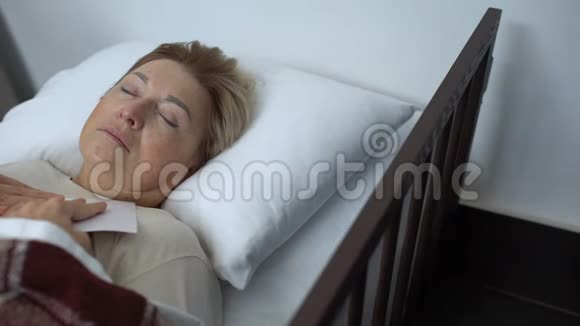 生病的护士用毯子覆盖睡眠中的老年病人拍摄全家福视频的预览图