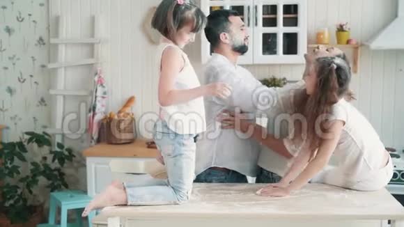 父母和女儿在厨房里被面粉弄脏了笑玩慢动作视频的预览图