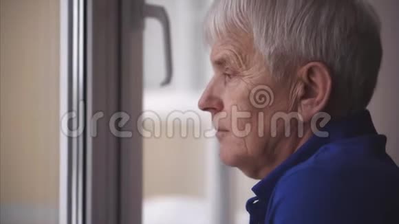 灰色老人脸上蓝眼睛的肖像他看着窗户视频的预览图