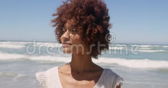 年轻的非裔美国妇女在阳光下海滩散步的正面景色视频的预览图