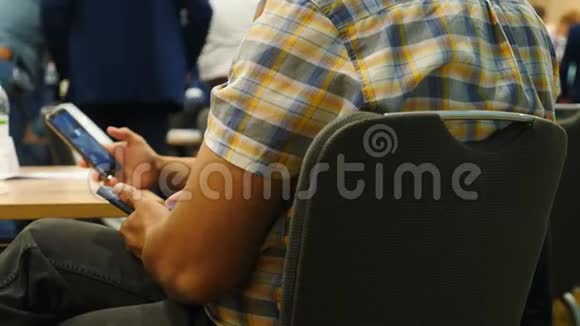 在商务会议商务会议或演讲研讨会上穿着支票衬衫的男士手持手机滚动视频的预览图