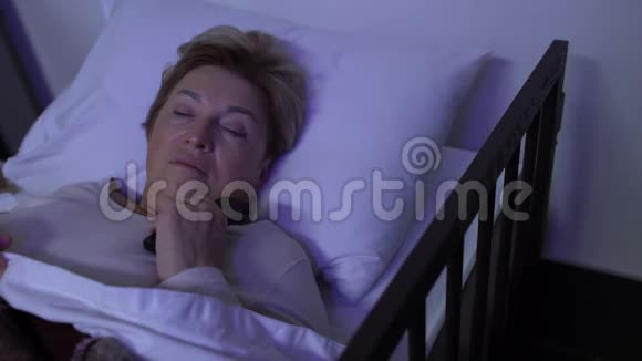 悲伤的成熟女性关掉电视躺在床上思考生活问题视频的预览图