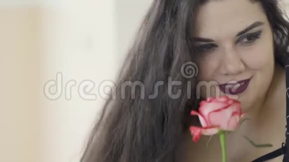 有魅力的超重女孩在室内嗅玫瑰的特写肖像头发随风飘动性感丰满视频的预览图