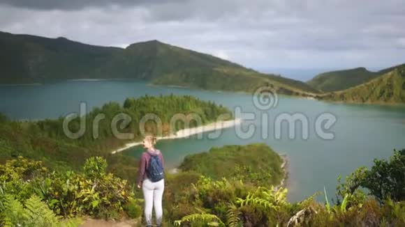 一位年轻的女游客站在一个俯瞰大海的高山湖附近视频的预览图