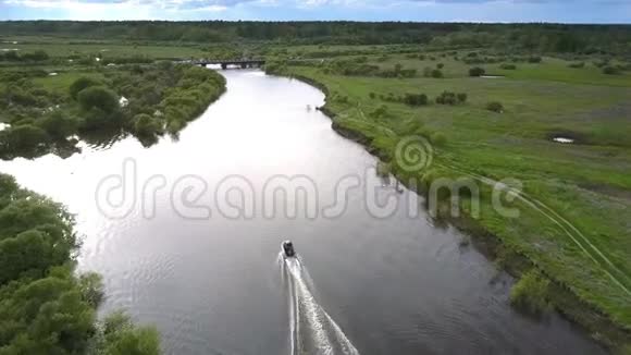 黑色摩托艇在草地桥附近的河边航行视频的预览图