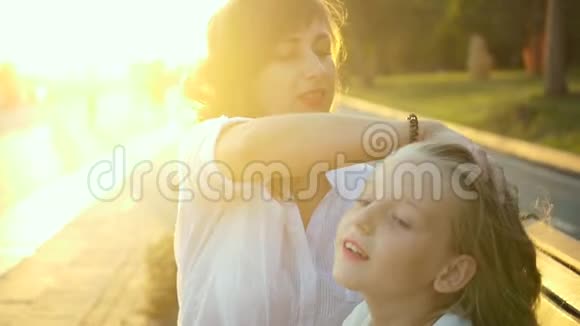 美丽的年轻母亲和她的女儿在公园里玩得很开心妈妈照顾她的女儿把她的头发剪直视频的预览图