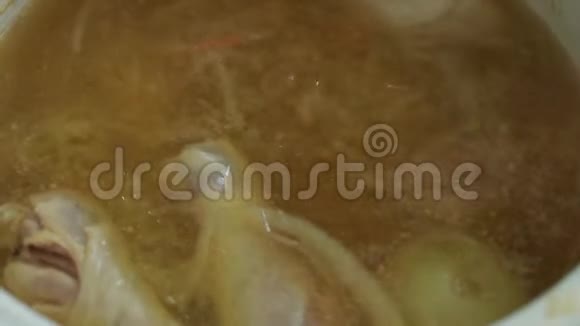 煮汤鸡肉和蔬菜和整个洋葱都是用平底锅煮的用勺子搅拌蒸汽来自熟食店视频的预览图