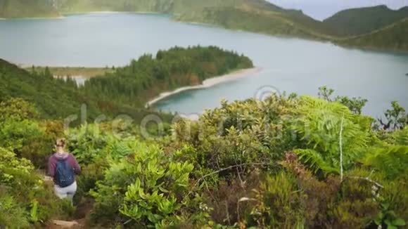 游客沿着茂密的植被中的一条山路在火山口欣赏美丽的湖景视频的预览图