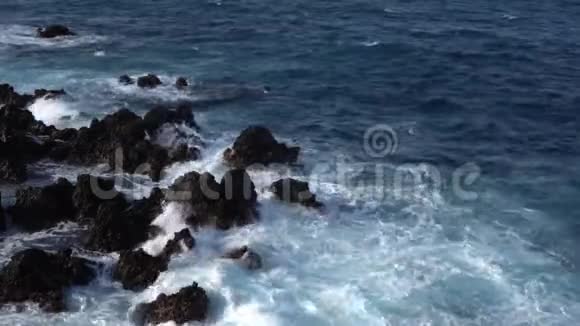 一股白色的波浪撞击着大西洋沿岸的黑色熔岩视频的预览图
