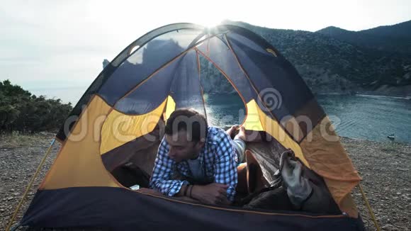 一个男人打电话给朋友亲戚或男朋友给他看帐篷露营的美丽地方视频的预览图