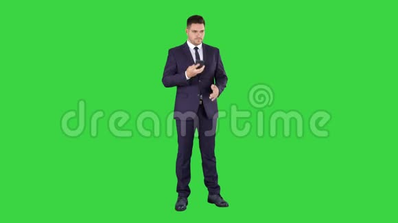 体贴的年轻商人穿着西装打着领带在绿色屏幕上快速打了几个电话色度键视频的预览图