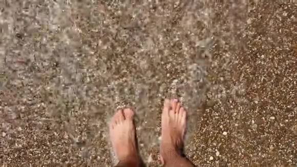 雄脚沿着海滨走雄性喜欢在卵石海滩上的海浪一个男人喜欢在鹅卵石滩上放松视频的预览图