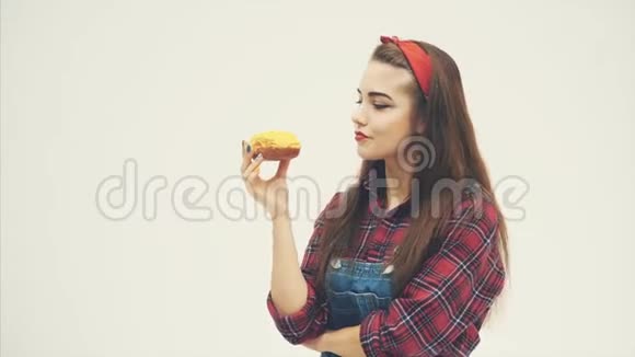 美丽可爱的年轻女孩品尝迷人的美味甜甜圈与黄色结冰显示出她的认可视频的预览图