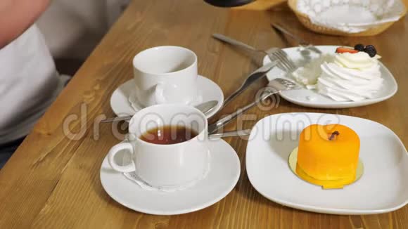 在舒适的现代咖啡馆里男人把美味的茶倒进女人的杯子里视频的预览图