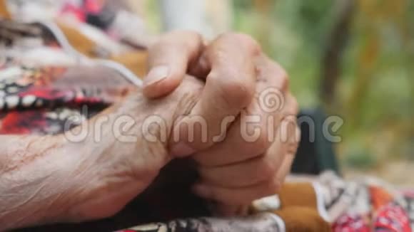 祖母在外面按摩她的皱纹手老妇人在户外照顾她的手臂关闭侧视视频的预览图