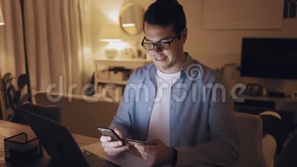 快乐男人在家里用信用卡在手机上购物视频的预览图
